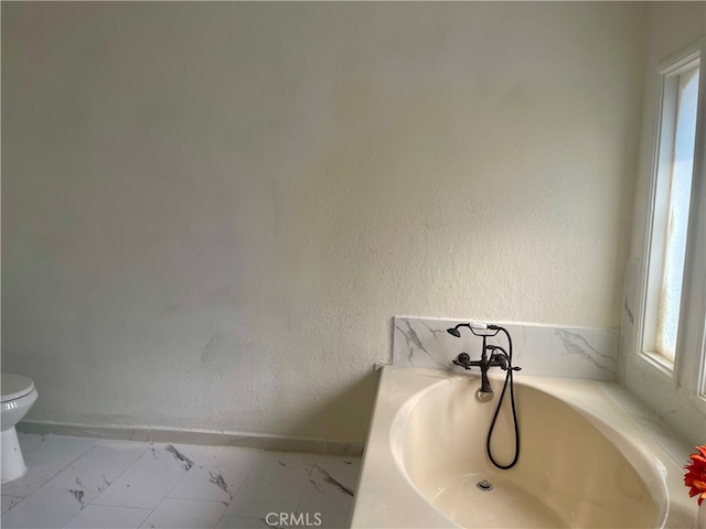 bathroom featuring toilet, a washtub, and a healthy amount of sunlight