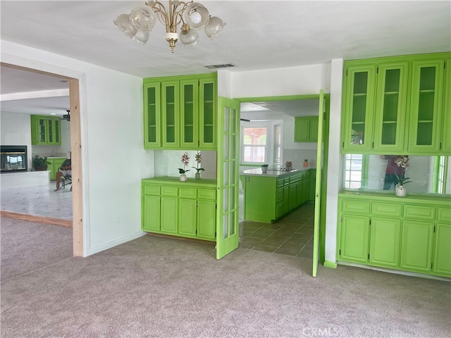 kitchen featuring green cabinetry, a chandelier, and light colored carpet