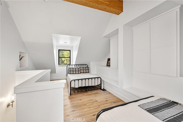 bedroom with vaulted ceiling with beams and light hardwood / wood-style floors