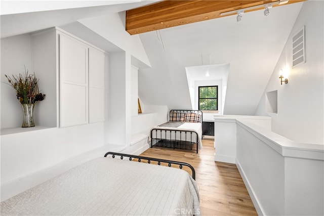 bedroom featuring light wood-type flooring and vaulted ceiling with beams