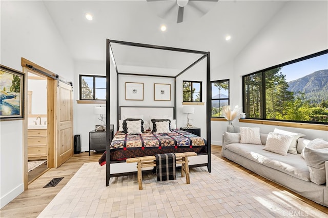 bedroom with a barn door, a mountain view, multiple windows, and ceiling fan