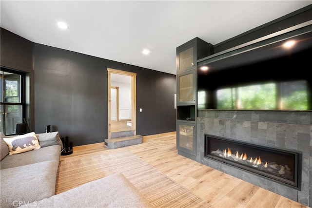 living room with light wood-type flooring and a tiled fireplace