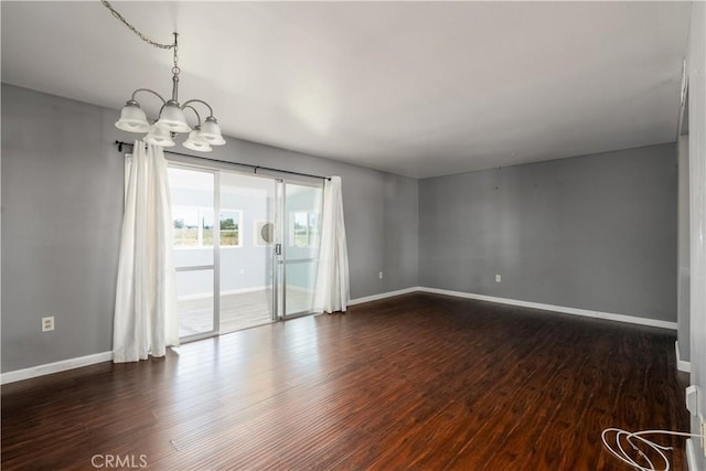 empty room with dark wood-type flooring and an inviting chandelier