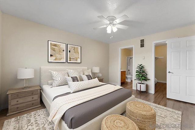 bedroom with ceiling fan, connected bathroom, a walk in closet, a closet, and dark hardwood / wood-style flooring