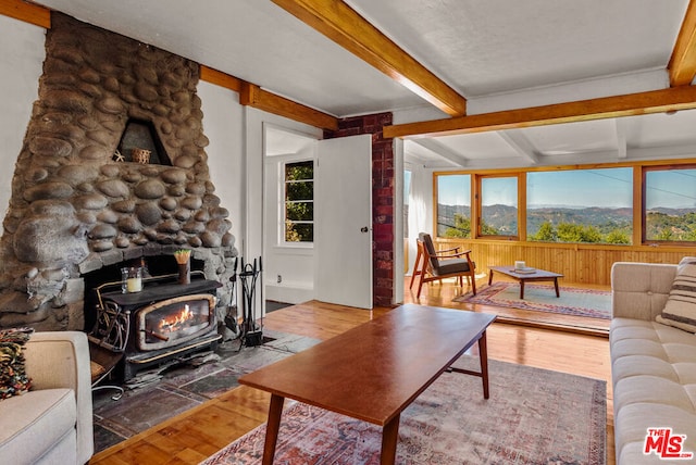 living room with beam ceiling, a wood stove, a mountain view, and wood-type flooring