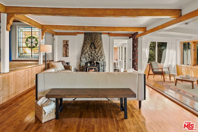 dining area featuring hardwood / wood-style flooring, a wood stove, and beamed ceiling