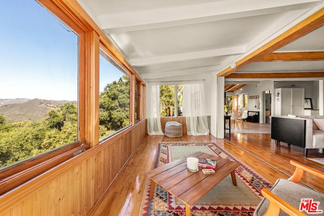 sunroom / solarium featuring a mountain view and lofted ceiling with beams