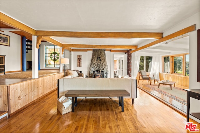 bedroom with hardwood / wood-style floors, a fireplace, and beamed ceiling