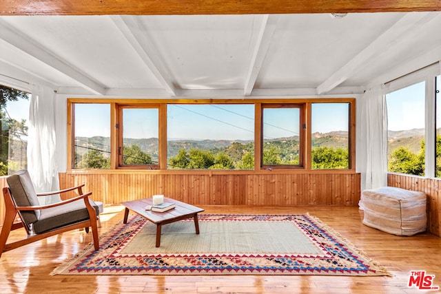 sunroom / solarium with a mountain view, beam ceiling, and a healthy amount of sunlight