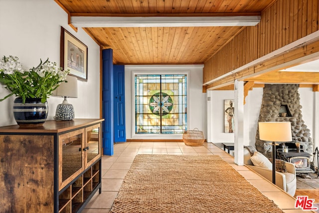 interior space with wood ceiling, beam ceiling, light tile patterned floors, and a wood stove