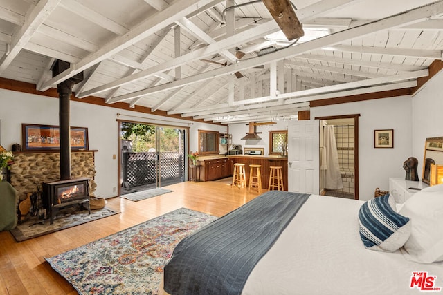 bedroom featuring vaulted ceiling with beams, wooden ceiling, a wood stove, access to outside, and light hardwood / wood-style floors