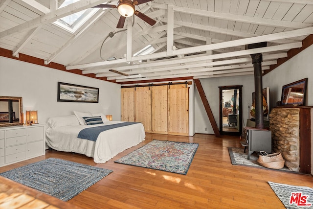 bedroom featuring a wood stove, vaulted ceiling with beams, wood ceiling, and light wood-type flooring