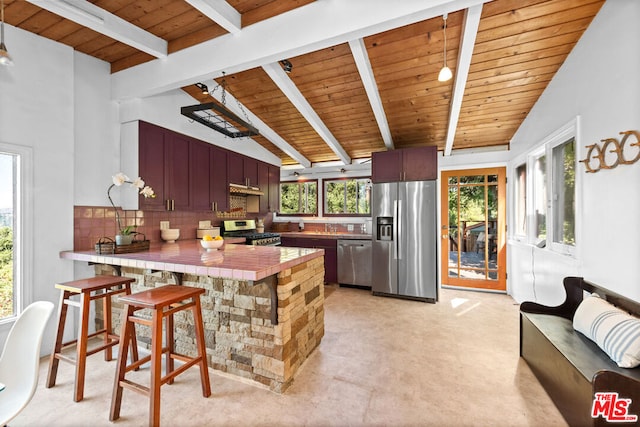 kitchen featuring a breakfast bar area, appliances with stainless steel finishes, decorative backsplash, tile countertops, and kitchen peninsula