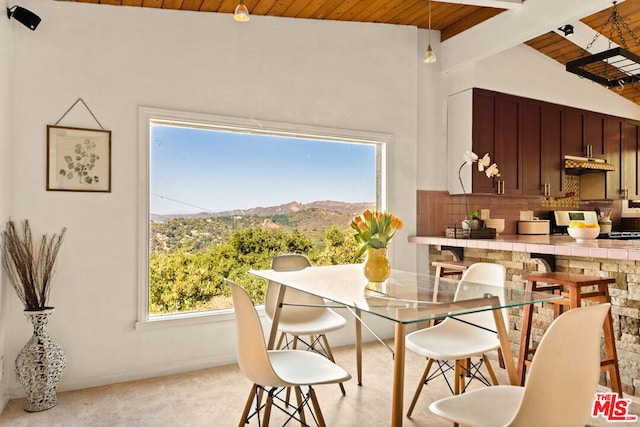 dining space with beamed ceiling, a mountain view, and wooden ceiling