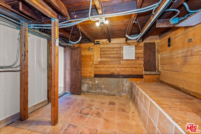 basement featuring tile patterned floors and wooden walls