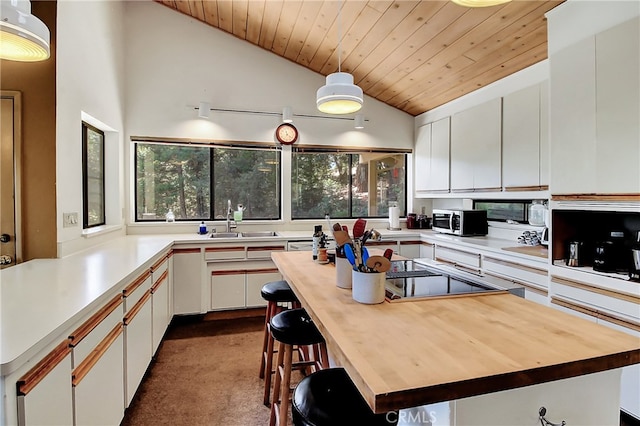 kitchen featuring lofted ceiling, white cabinets, dark colored carpet, and a wealth of natural light