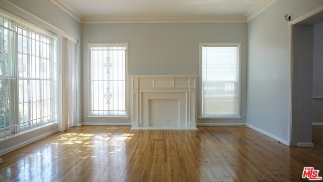 unfurnished living room with hardwood / wood-style floors and crown molding