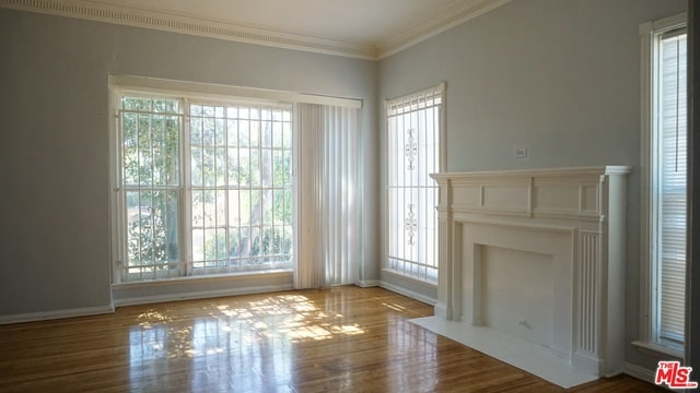 unfurnished living room featuring hardwood / wood-style flooring, a healthy amount of sunlight, and crown molding