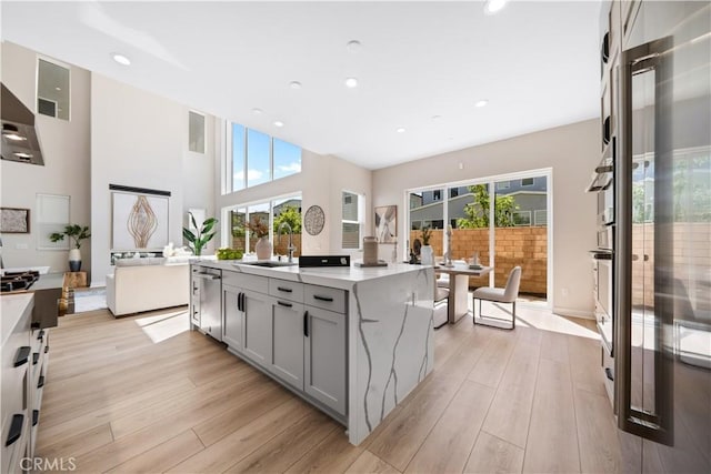 kitchen with gray cabinetry, light stone counters, a kitchen island, and a healthy amount of sunlight