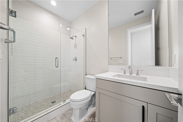 bathroom with tile patterned flooring, a shower with door, vanity, and toilet