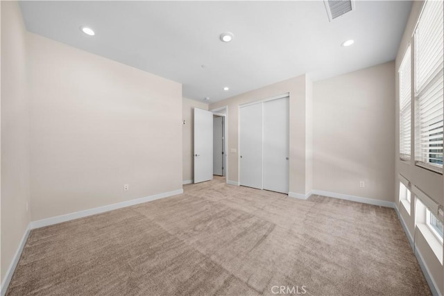 unfurnished bedroom featuring light carpet and a closet