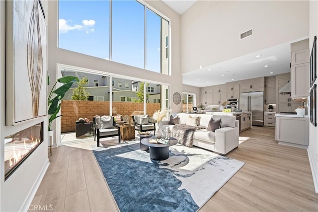 living room with light hardwood / wood-style flooring and a towering ceiling