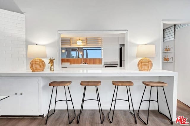 kitchen with white cabinets, stainless steel oven, dark wood-type flooring, and kitchen peninsula