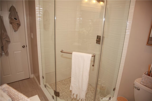 bathroom with a shower with shower door and toilet