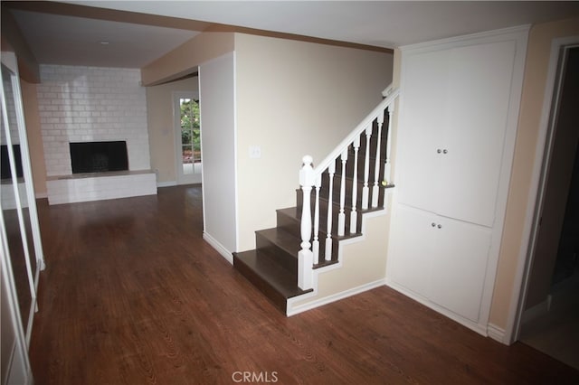 stairs featuring a brick fireplace and hardwood / wood-style flooring