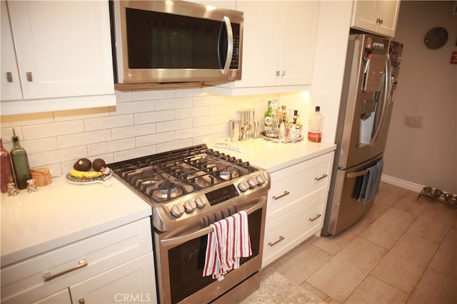 kitchen with white cabinets, stainless steel appliances, light tile patterned floors, and decorative backsplash