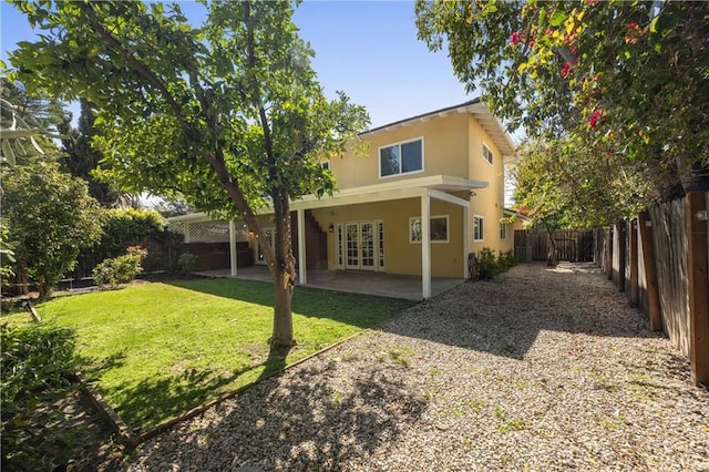 rear view of property with a fenced backyard, a yard, stucco siding, french doors, and a patio