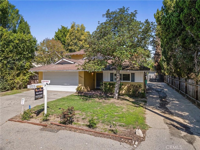 view of front of home featuring stucco siding, fence, driveway, and a garage