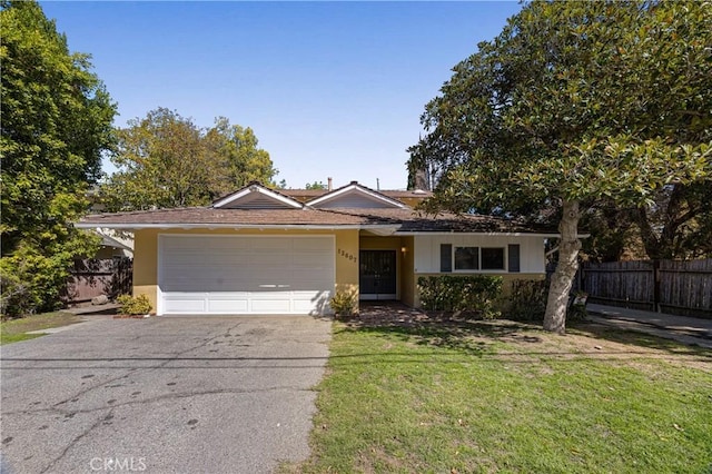 ranch-style house with a front lawn, aphalt driveway, an attached garage, fence, and stucco siding