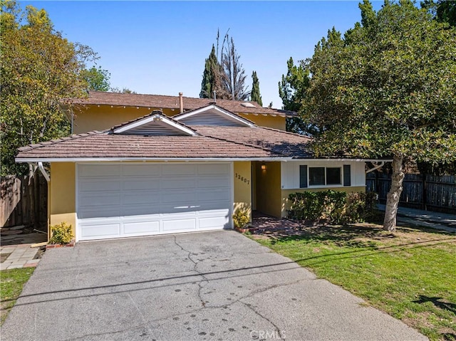 view of front facade featuring stucco siding, an attached garage, fence, and aphalt driveway