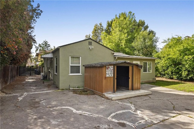 exterior space featuring an outdoor structure, a shed, stucco siding, and fence