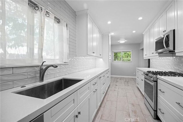 kitchen featuring a sink, decorative backsplash, stainless steel appliances, white cabinets, and recessed lighting