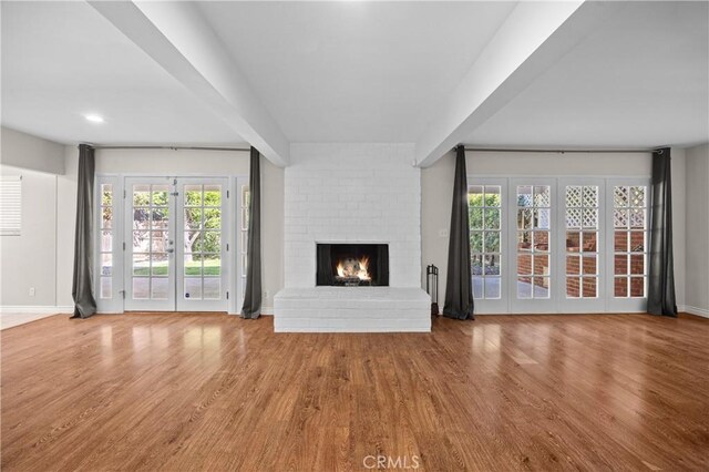 unfurnished living room with baseboards, wood finished floors, and a fireplace