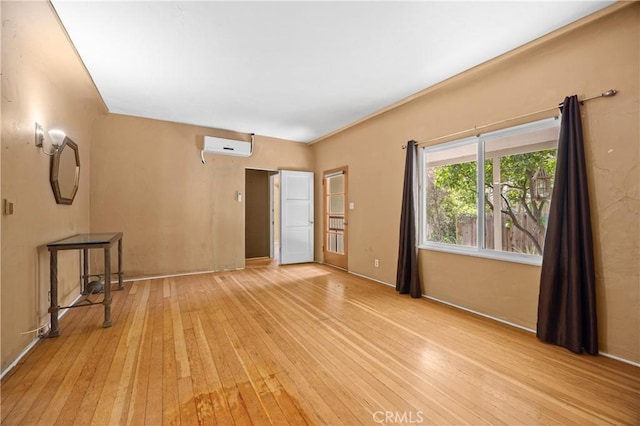 unfurnished living room featuring wood-type flooring, baseboards, and a wall unit AC