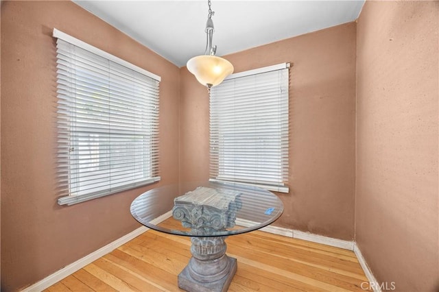 dining space with wood-type flooring and baseboards