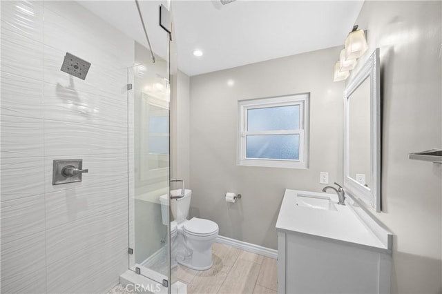 bathroom featuring toilet, baseboards, vanity, and a stall shower