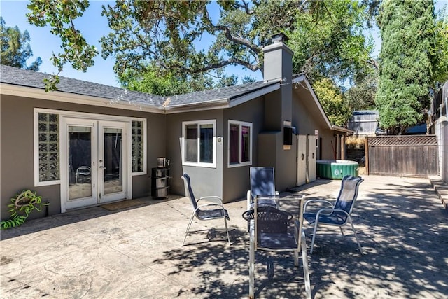 back of property featuring french doors, a hot tub, and a patio area