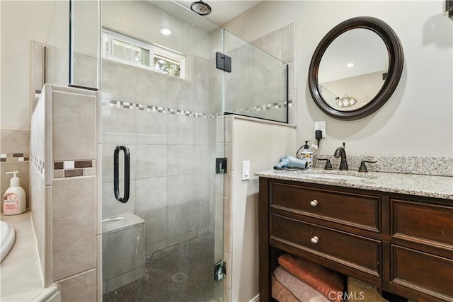 bathroom featuring a shower with door and vanity