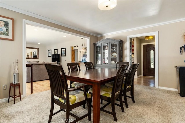 carpeted dining space with ornamental molding