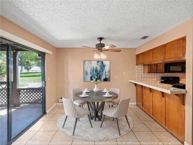 tiled dining space with ceiling fan and a textured ceiling