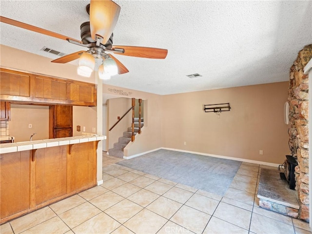 kitchen with ceiling fan, tile counters, a textured ceiling, and light tile patterned floors