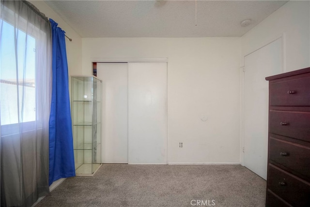 unfurnished bedroom featuring a textured ceiling and light colored carpet