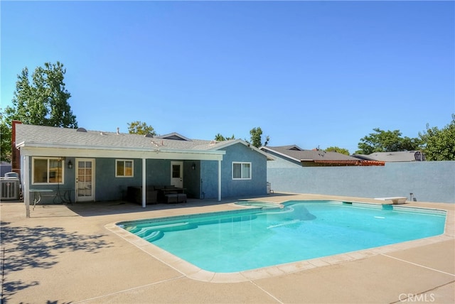 view of pool with a diving board, cooling unit, and a patio area