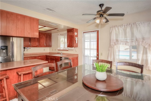 dining space with a textured ceiling, ceiling fan, and sink