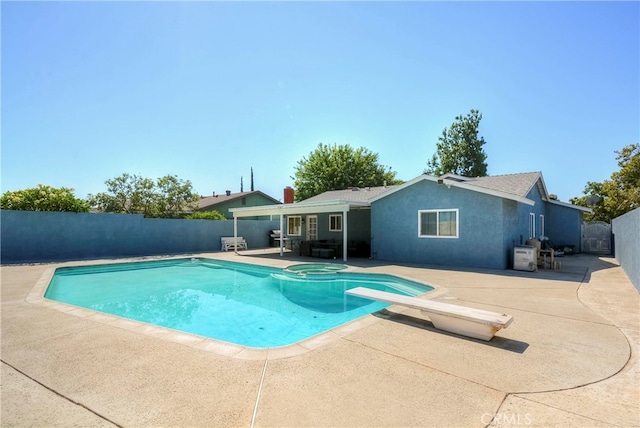 view of swimming pool featuring a patio and a diving board