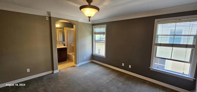 unfurnished bedroom with ensuite bathroom, crown molding, and carpet